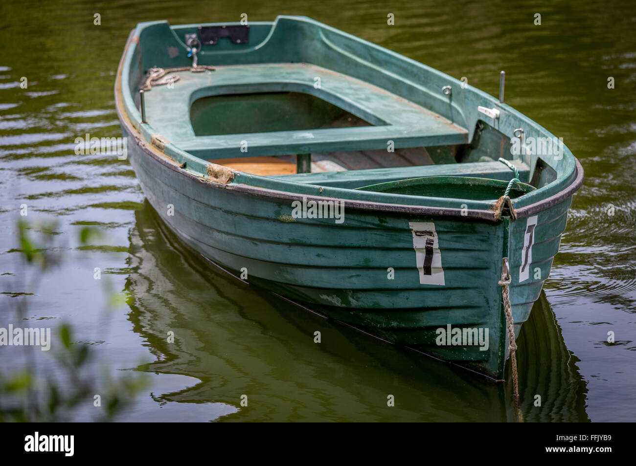 grüne Boot Schlauchboot schwimmt auf Wasser mit einem Fokus Strauch im Vordergrund Stockfoto
