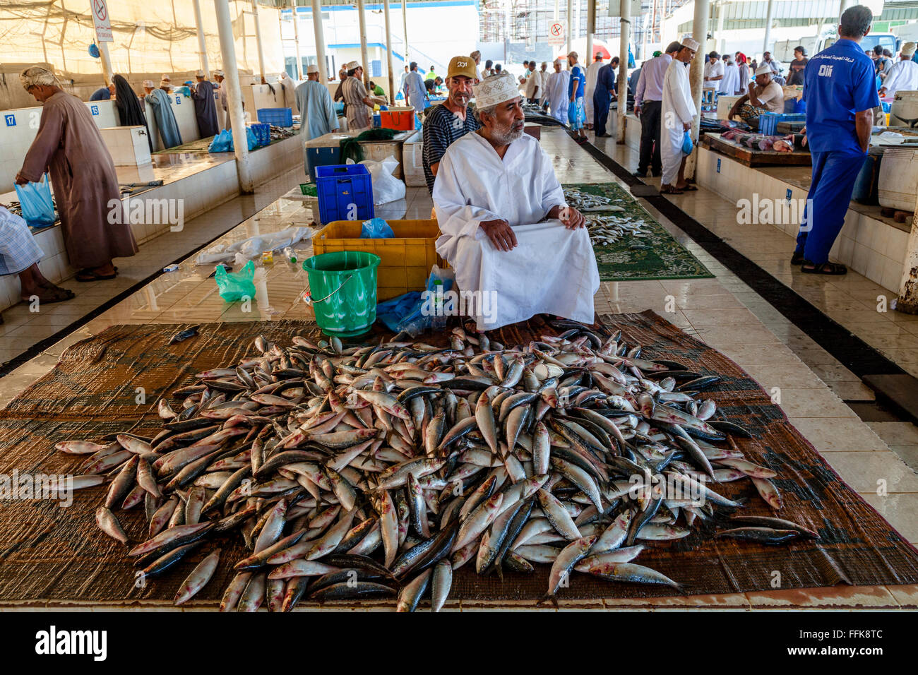 Ein omanischer Mann In traditioneller Kleidung verkauft Fisch auf dem Fischmarkt, Muttrah, Muscat, Sultanat von Oman Stockfoto