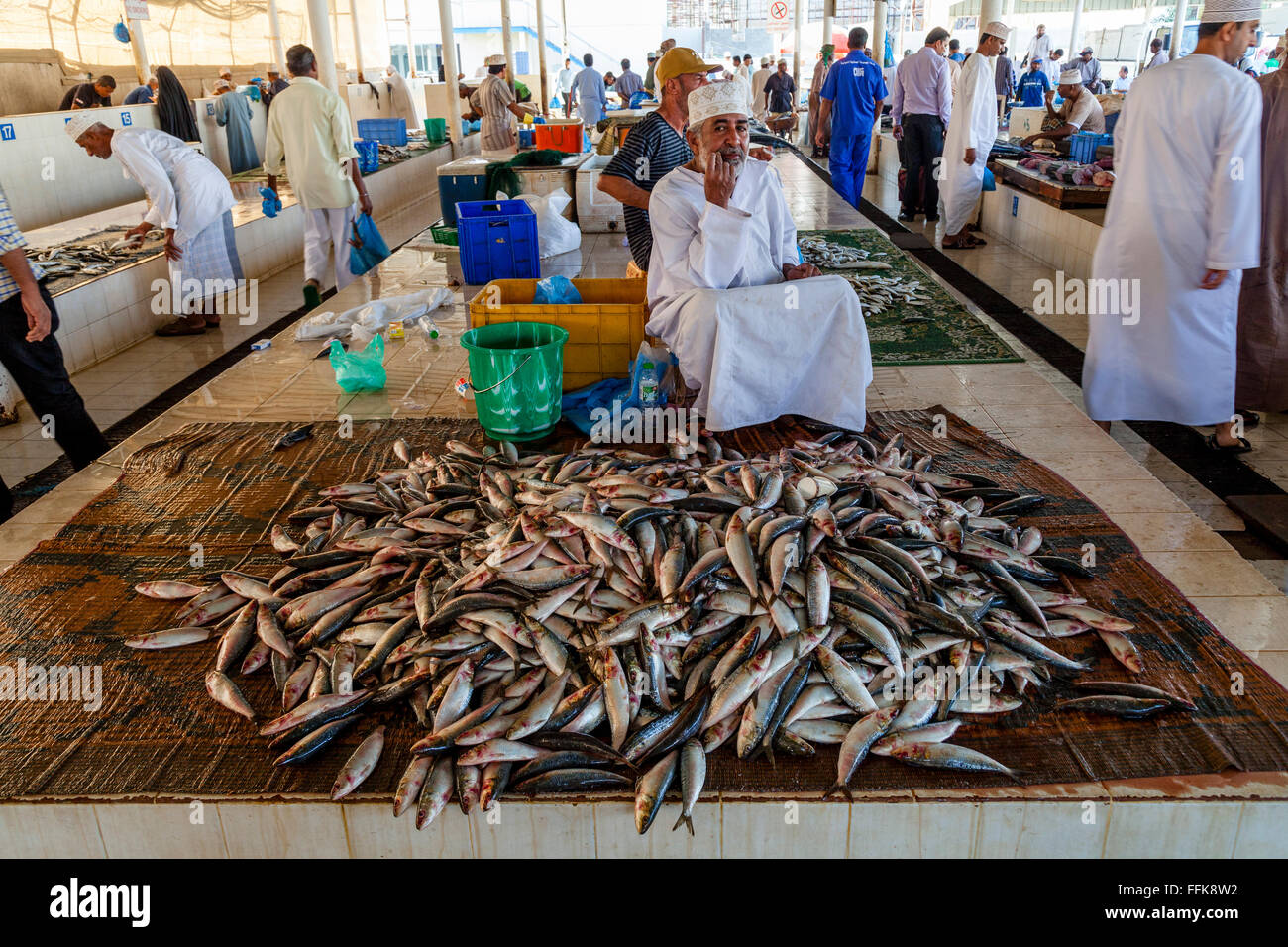 Ein omanischer Mann In traditioneller Kleidung verkauft Fisch auf dem Fischmarkt, Muttrah, Muscat, Sultanat von Oman Stockfoto
