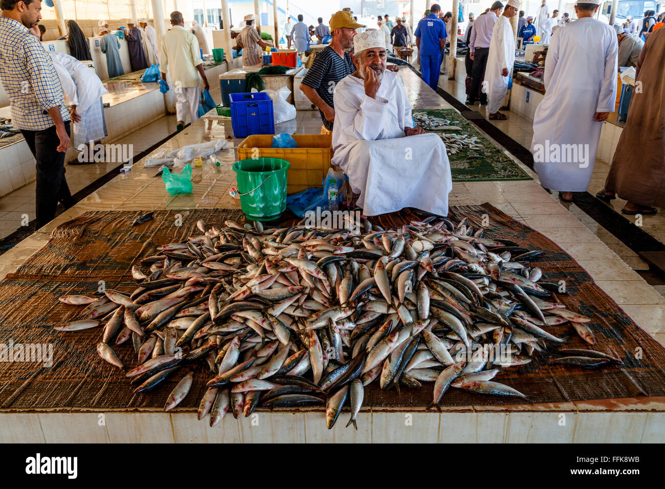 Ein omanischer Mann In traditioneller Kleidung verkauft Fisch auf dem Fischmarkt, Muttrah, Muscat, Sultanat von Oman Stockfoto