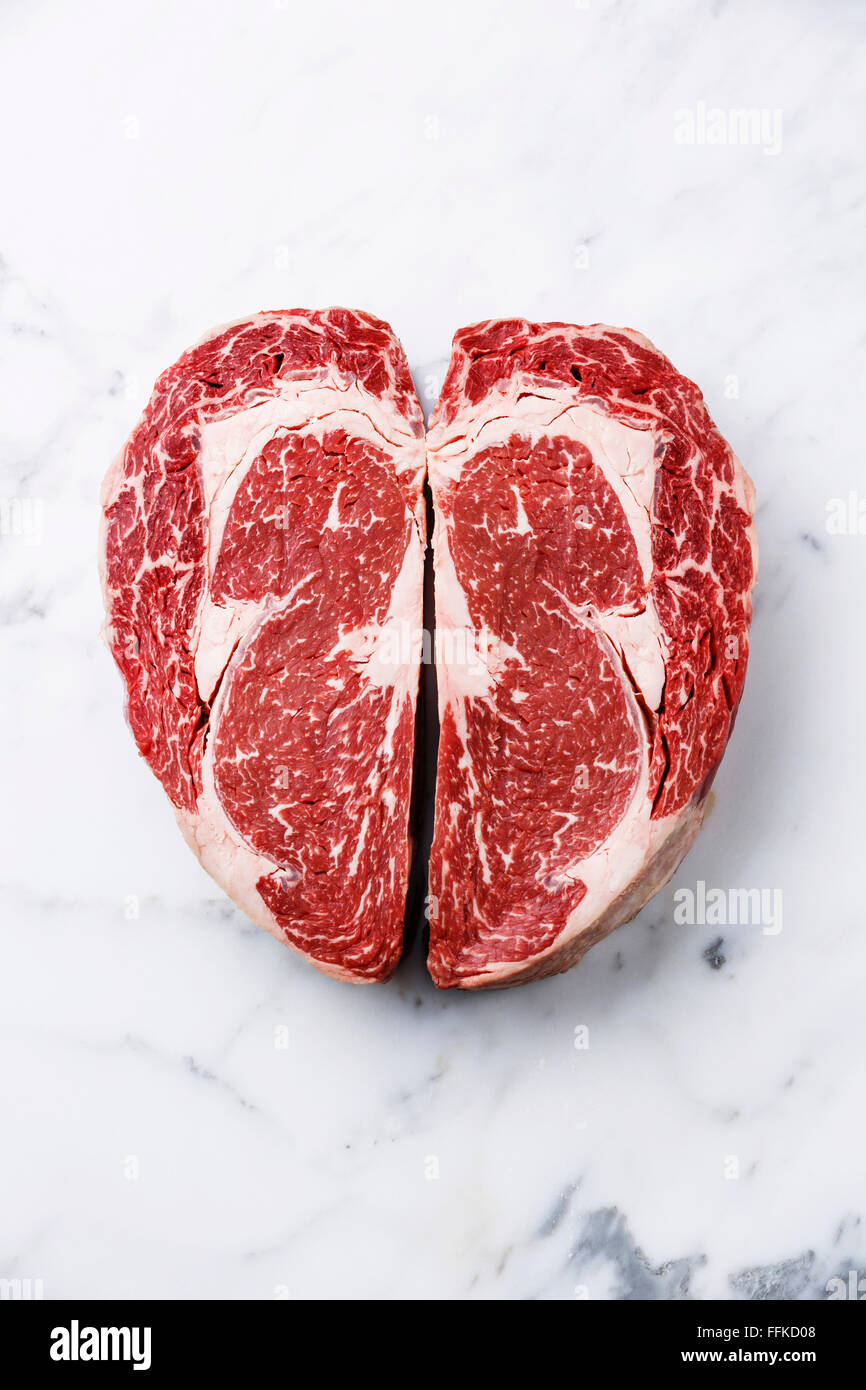 Herzform rohes Frischfleisch Ribeye Steak auf weißem Marmor Hintergrund Stockfoto