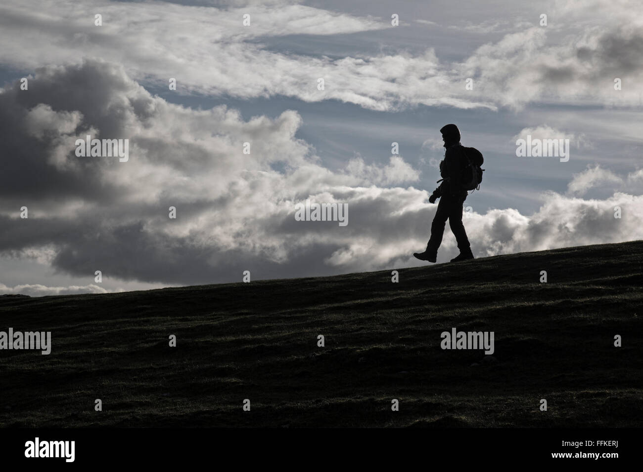 Eine einsame weibliche Wanderer Silhouette gegen ein bewölkter Himmel. Stockfoto