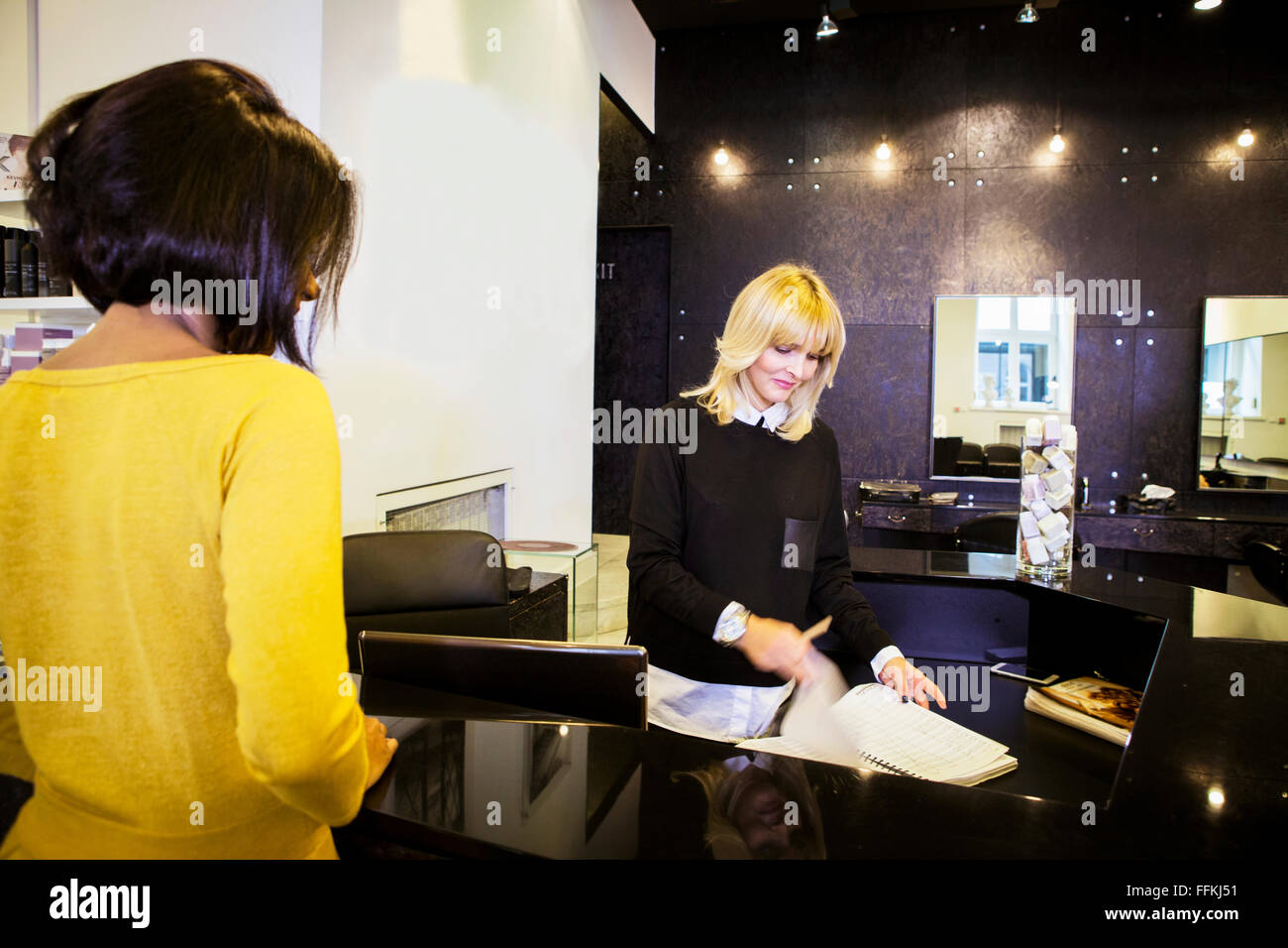 Kunden und Angestellte an der Rezeption im Friseursalon Stockfoto