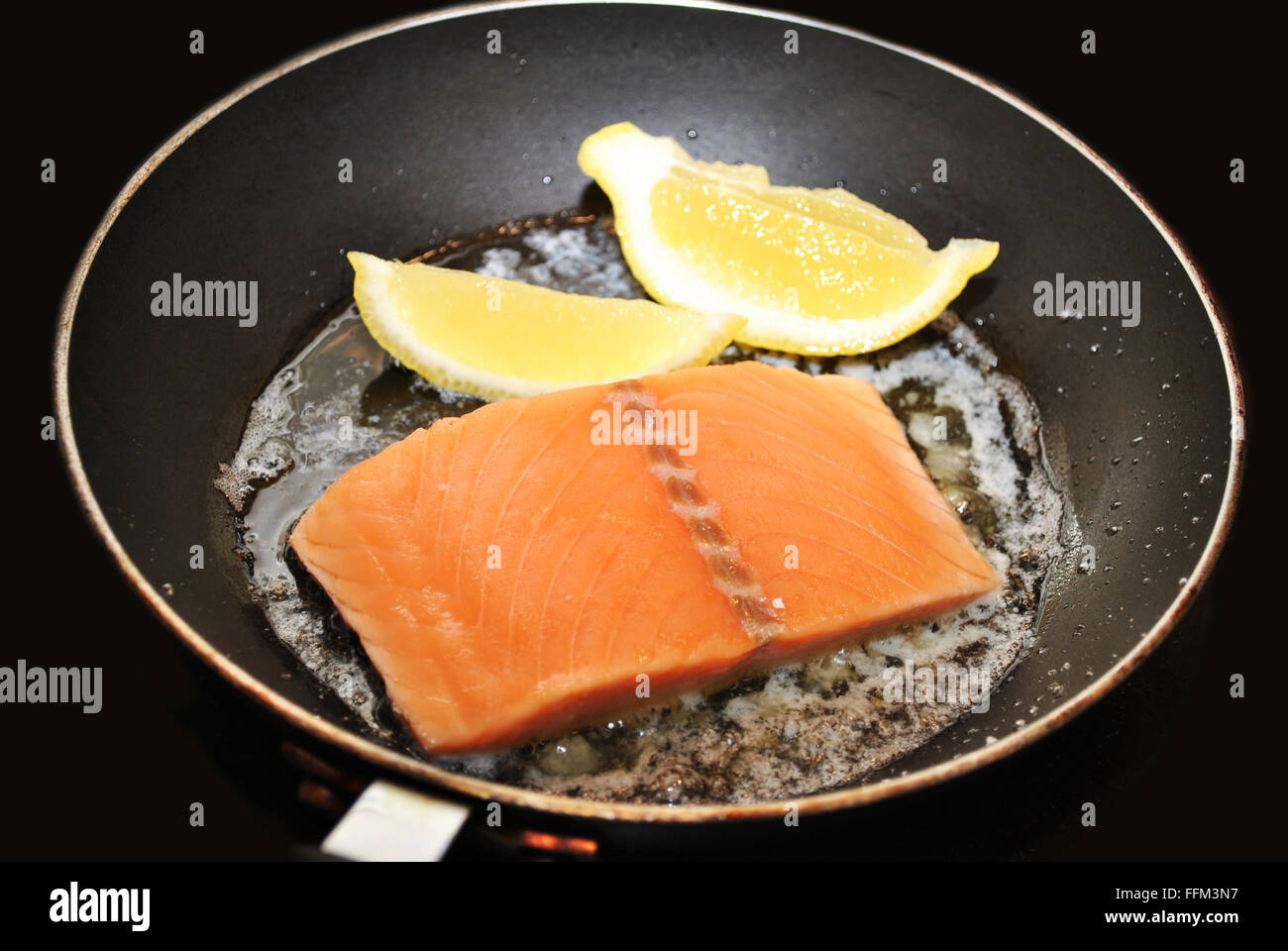 Roher Lachs mit Butter und Zitrone in einer Pfanne anbraten Stockfoto