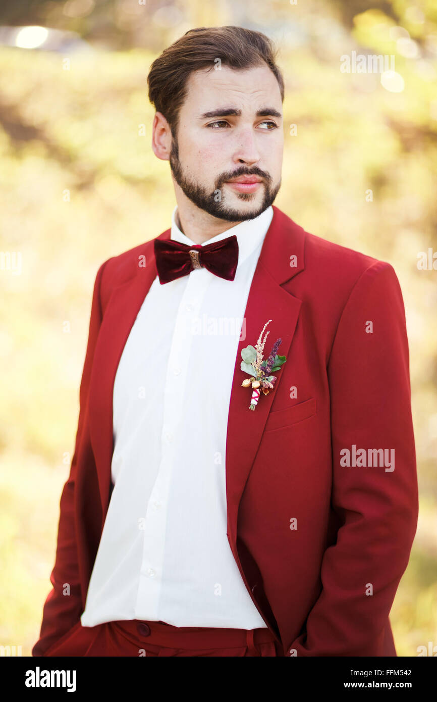 Porträt des Bräutigams, roten Anzug mit einem Knopfloch-Blume. Hochzeit im  Stil Marsala Farbe Stockfotografie - Alamy