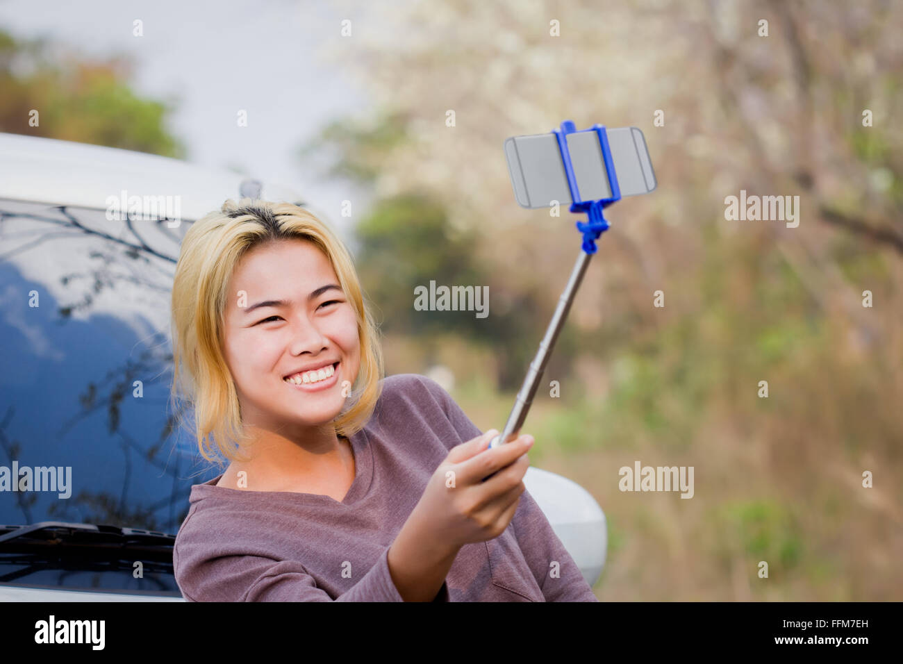 Glück-Mädchen hält Selfie Stock fotografieren auf der Straße neben der natürlichen Schönheit Stockfoto