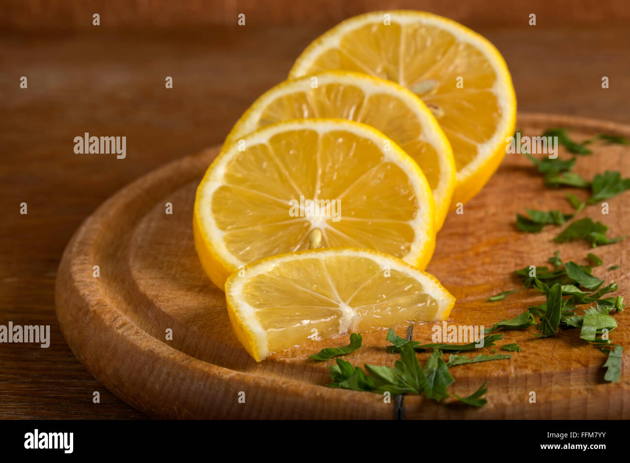 In Scheiben geschnittenen Zitrone auf dem hölzernen Schneidebrett mit Petersilie Stockfoto