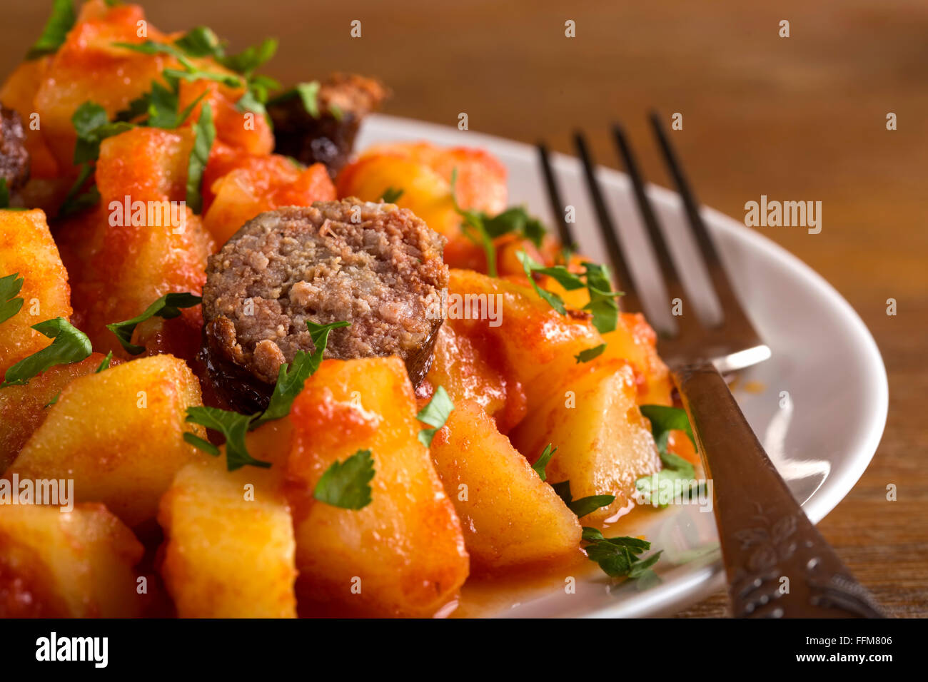 Kartoffel-Wurst-Dinner am weißen Teller mit Silber Gabel Stockfoto