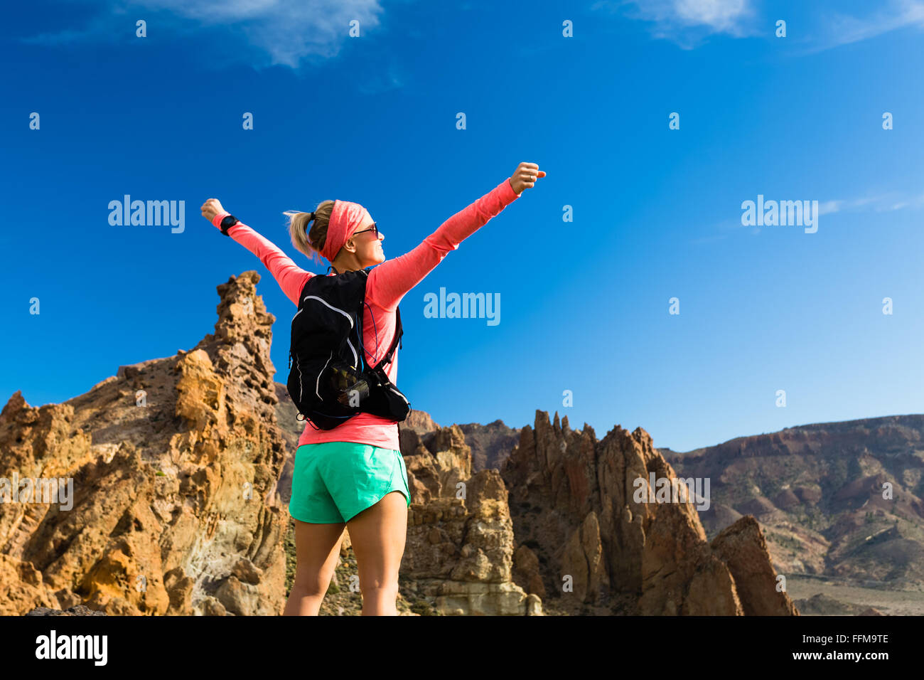 Frau Wanderer mit ausgestreckten in Bergen. Weibliche Schönheit Läufer, Hände hoch und genießen Sie inspirierende Landschaft auf felsigen Pfad Stockfoto