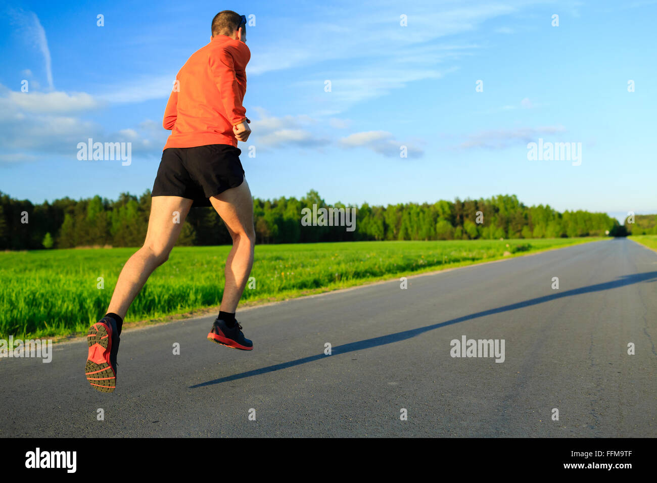 Mann-Läufer läuft auf Landstraße, Training Inspiration und Motivation im Sommer Sonnenuntergang. Junge Sportler männlich training und tun Stockfoto