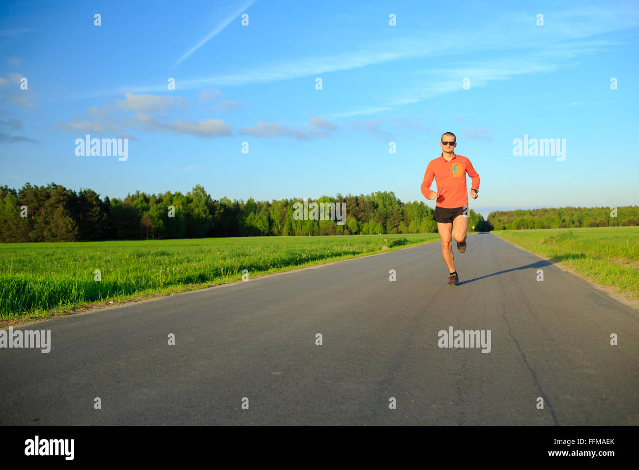 Mann-Läufer läuft auf Landstraße, Training Inspiration und Motivation im Sommer Sonnenuntergang. Junge Sportler männlich training und tun Stockfoto