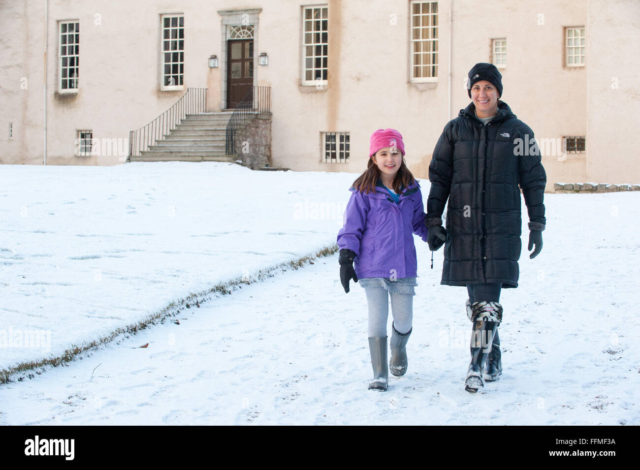 Mutter und Tochter Spaziergang im Schnee auf der Trommel Burg in Aberdeenshire, Schottland. Stockfoto