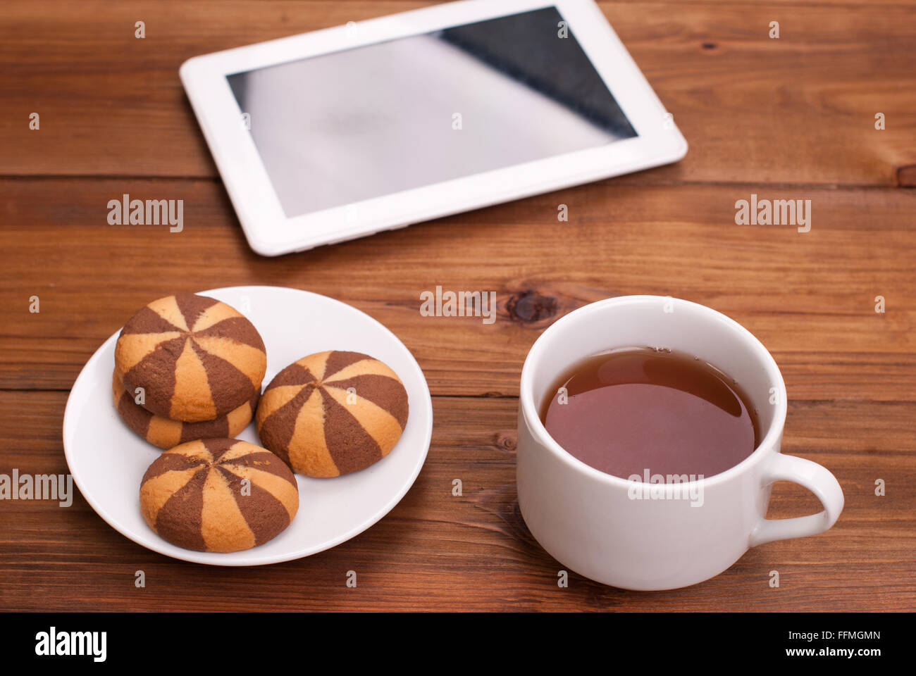 Tasse Tee und Gebäck ein digitales tablet auf dem Holztisch. Stockfoto