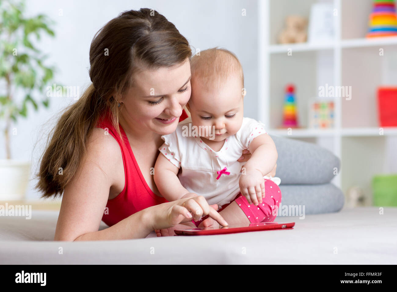 Mutter und Baby sind auf der Suche um Tablet-Computer auf der Couch zu Hause spielen Stockfoto