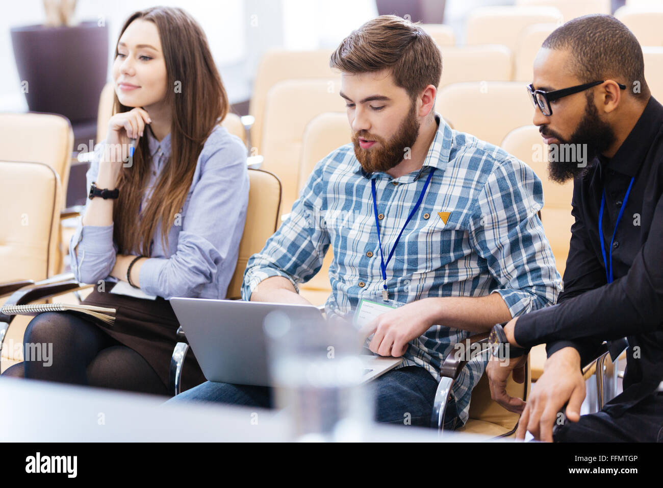Multiethnische Gruppe von jungen Geschäftsleuten mit Laptop sitzen auf Treffen im Konferenzsaal Stockfoto