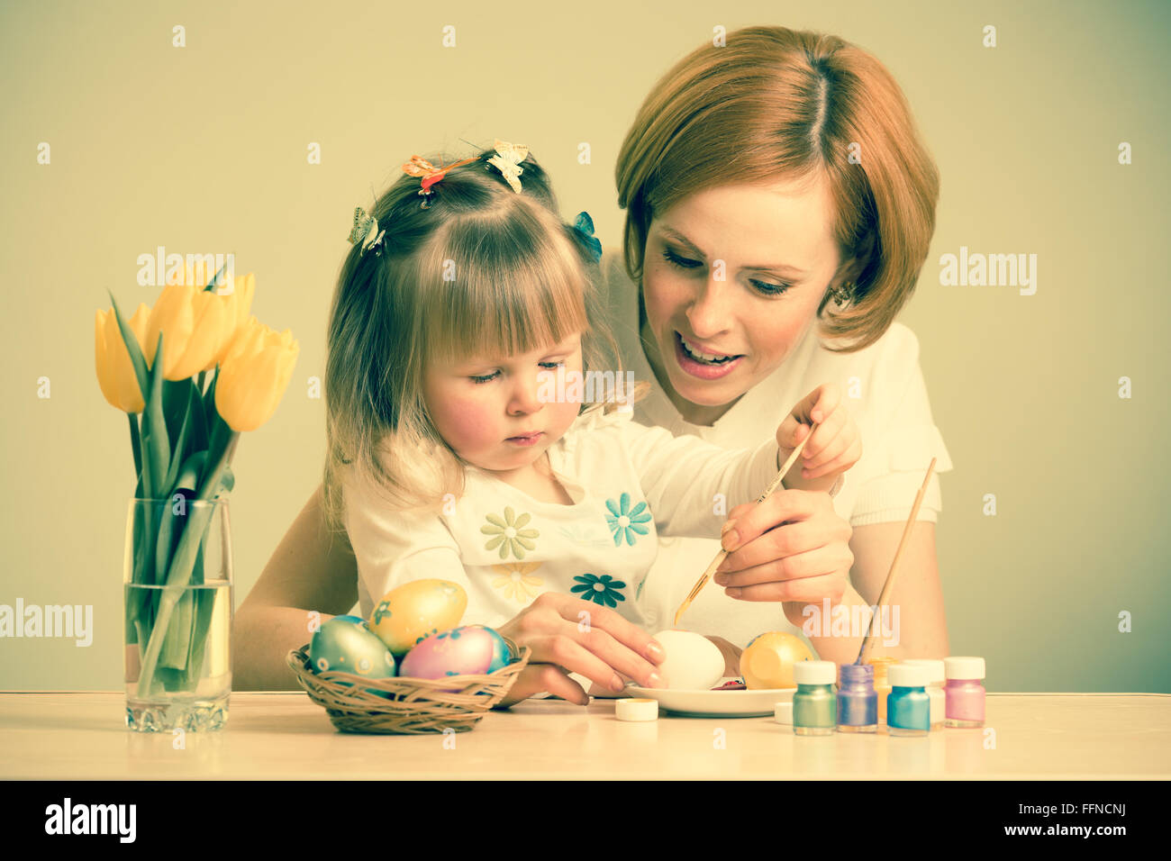 glückliche Mutter und Kind Tochter mit Pinsel Ostereier färben Stockfoto