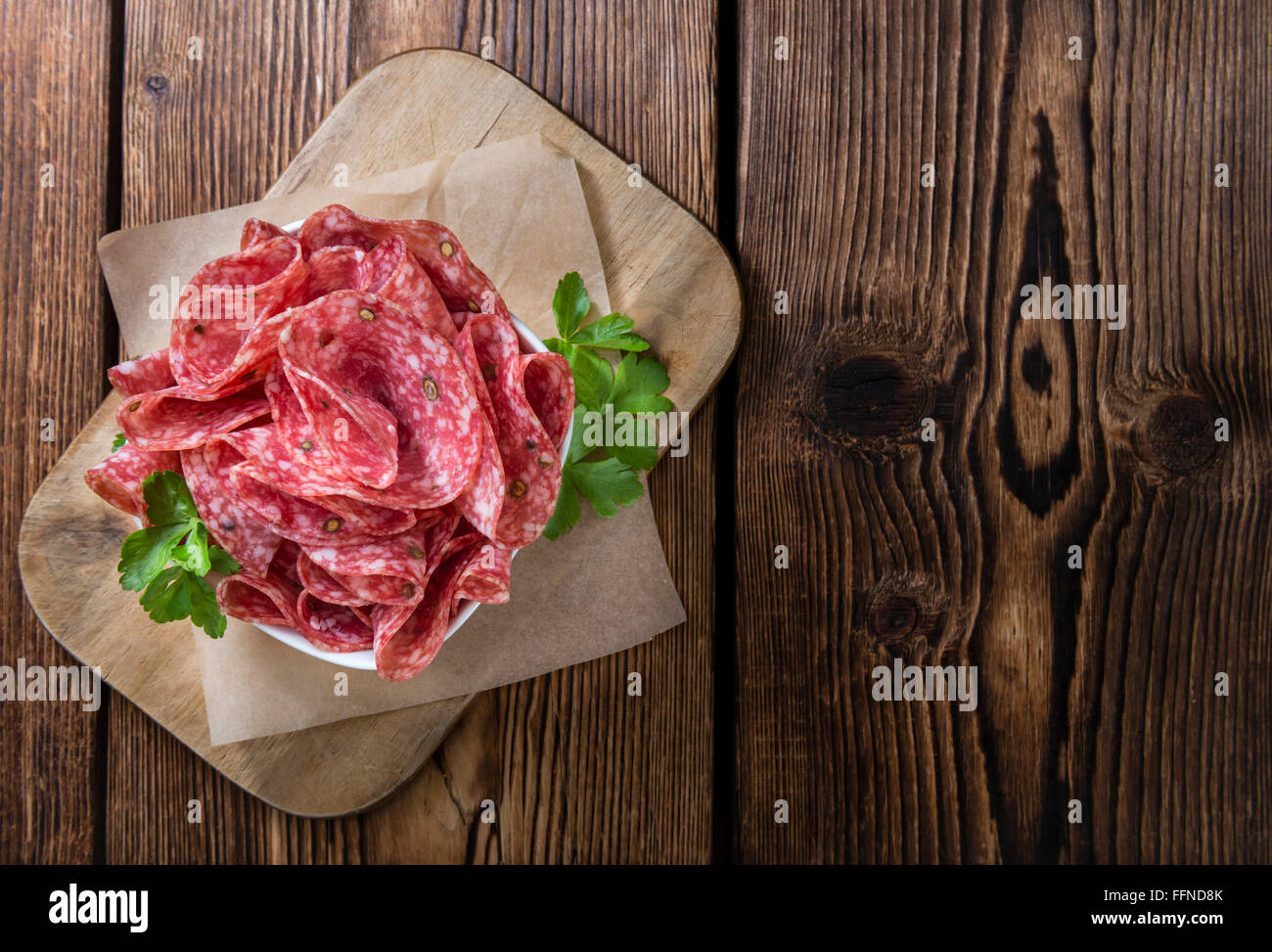 Scheiben Salami (Tiefenschärfe) auf einem alten Holztisch vintage Stockfoto