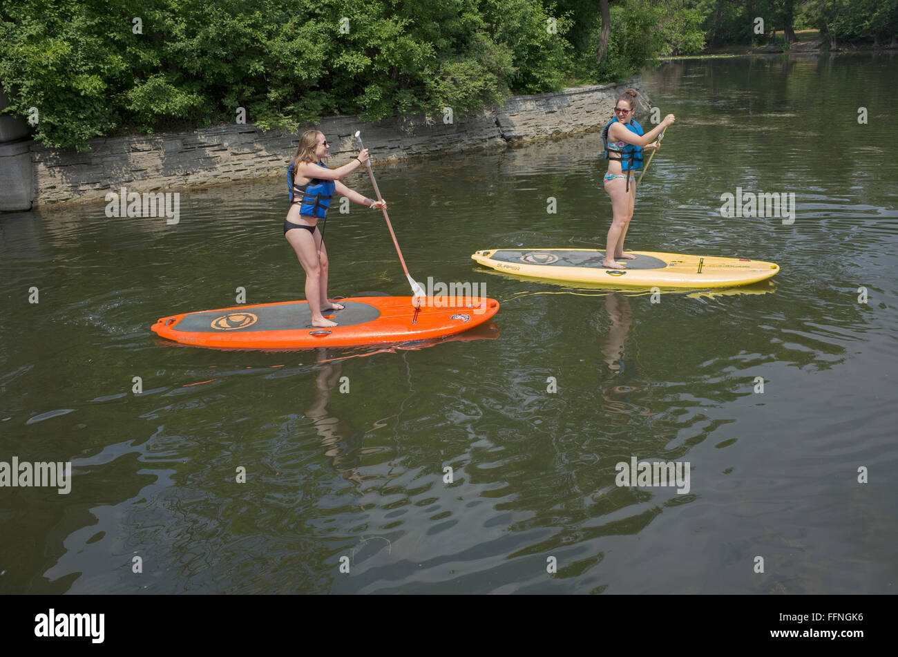 Teenager Frauen auf Paddleboards zwischen Lake Calhoun und See der Inseln mit Rettungswesten paddeln. Minneapolis Minnesota MN USA Stockfoto