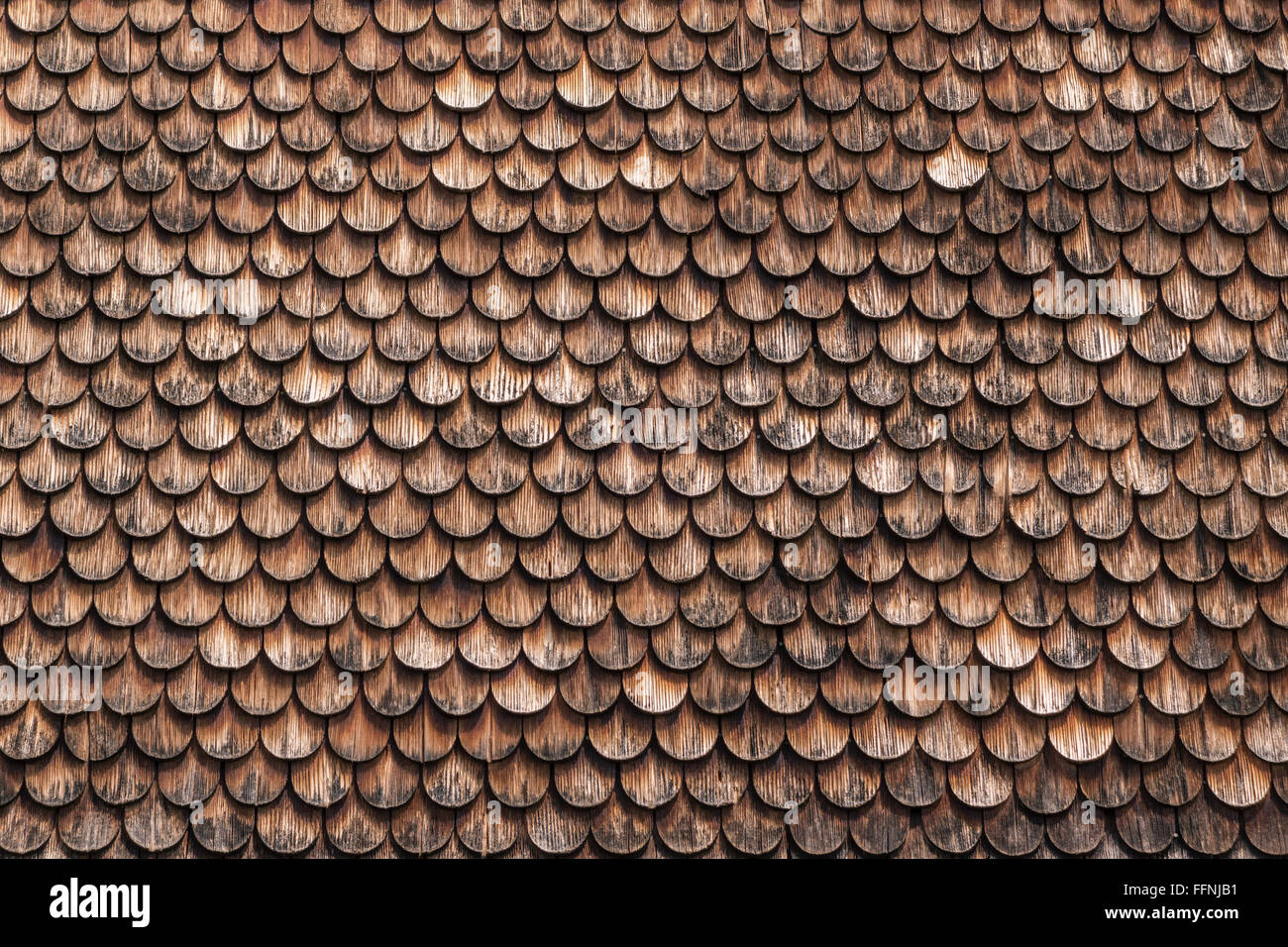 Braun, verwittert, kreisförmige Holzschindeln. An der Fassade eines Hauses in Bayern übernommen. Stockfoto