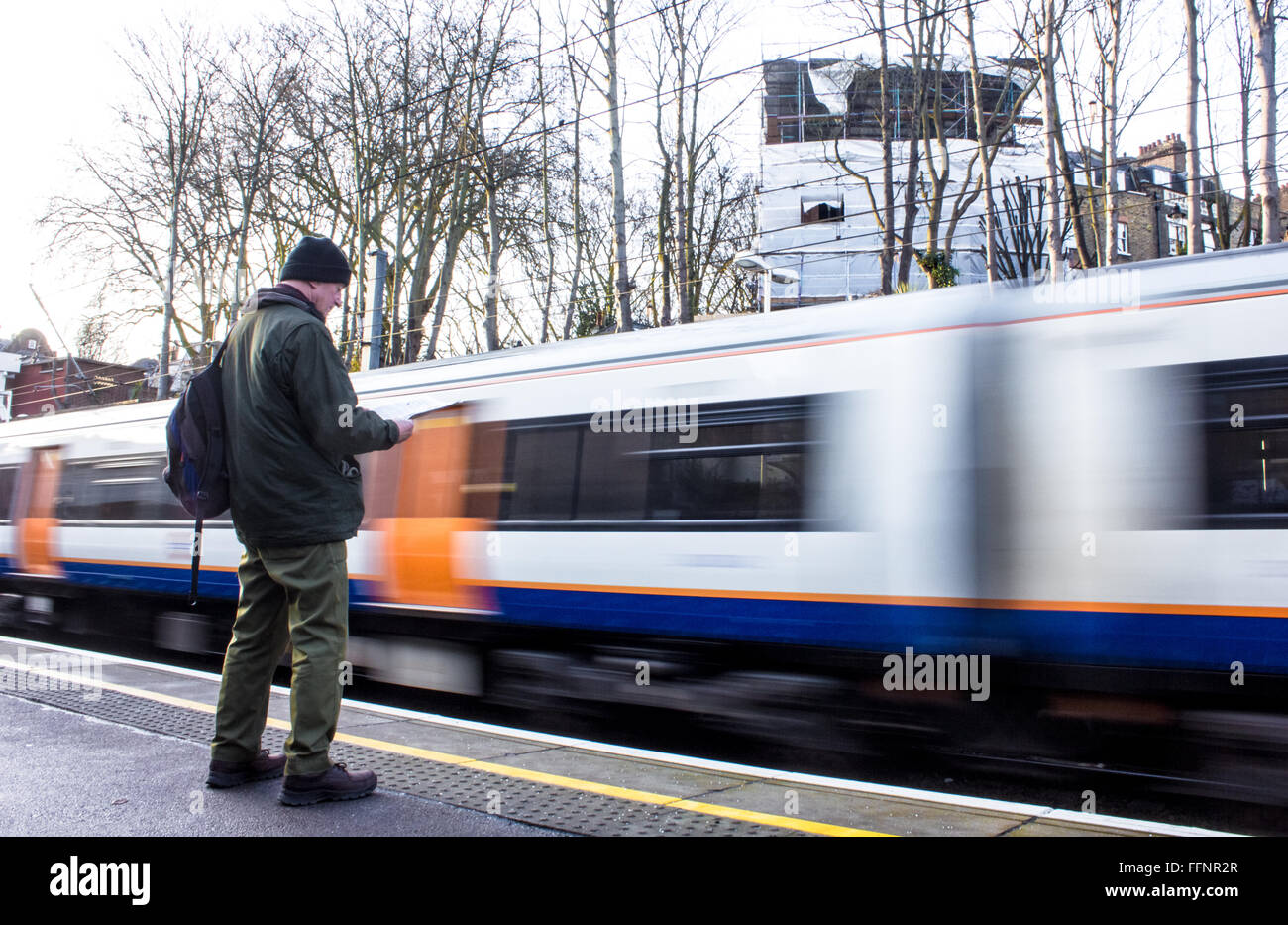 Oberirdischen Bahnhof verlassen Hampstead Heath Overground mit einem Mann eine Zeitung lesen, während der Wartezeit im Vordergrund. Stockfoto