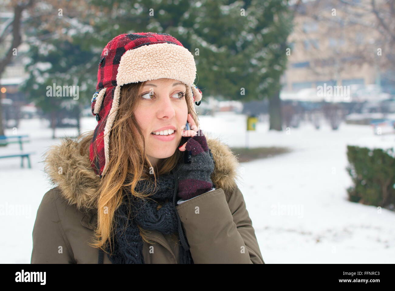 Mädchen mit einem Holzfäller Hut Gespräch über ihr Handy im Schnee Stockfoto