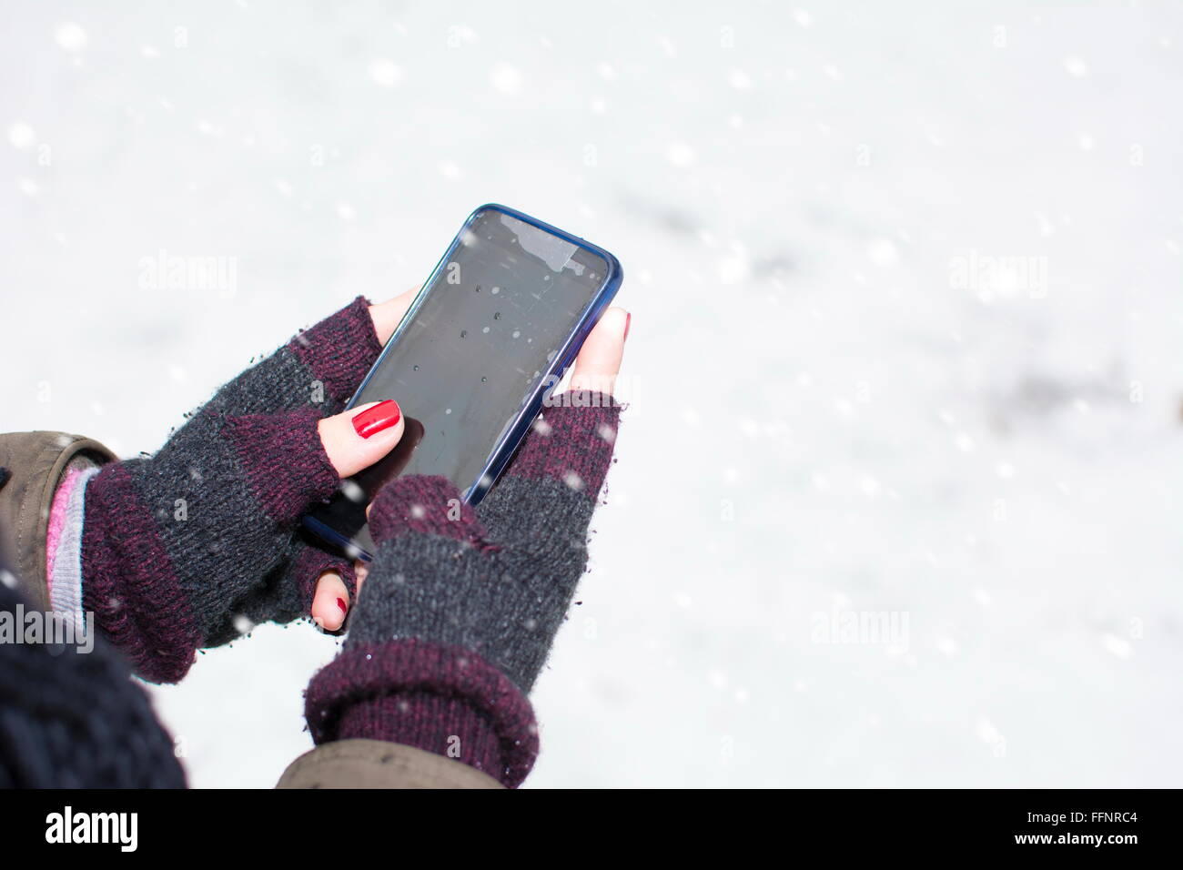 weibliche Hände in Handschuhe halten eine smartphone Stockfoto