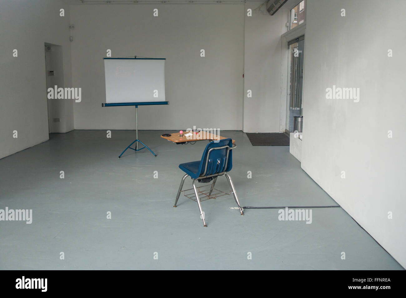 Einen Schreibtisch und ein Stuhl mit einem Bildschirm in einem leeren Raum Stockfoto