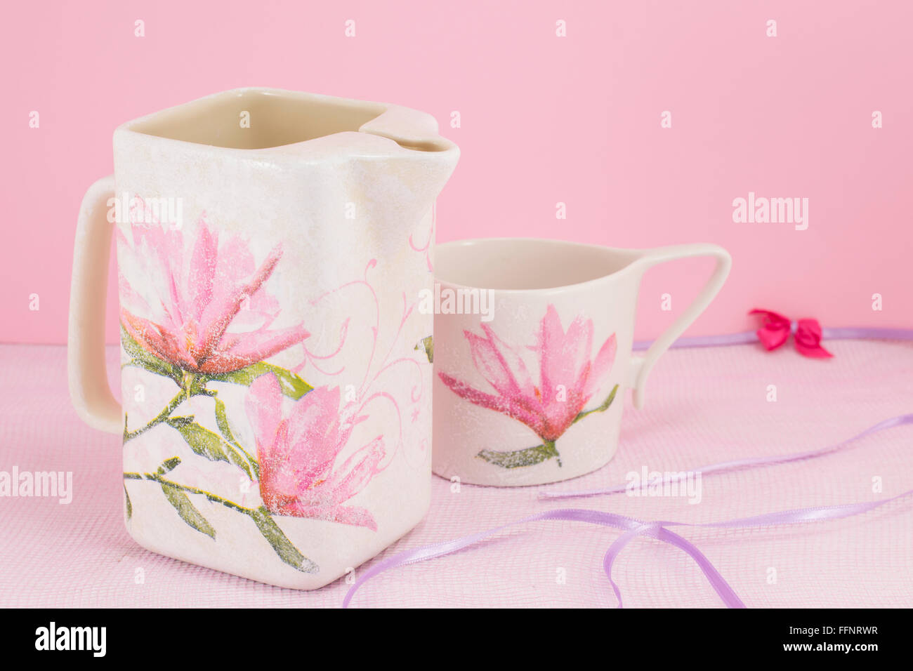 Serviettentechnik dekoriert, Teekanne und Teetasse vor rosa Hintergrund Stockfoto