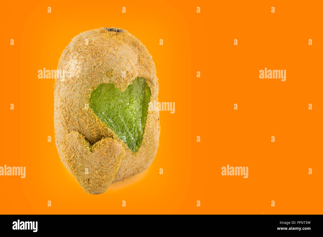 Kiwis mit Herzformen geschnitzt in seine Haut orange Hintergrund Stockfoto
