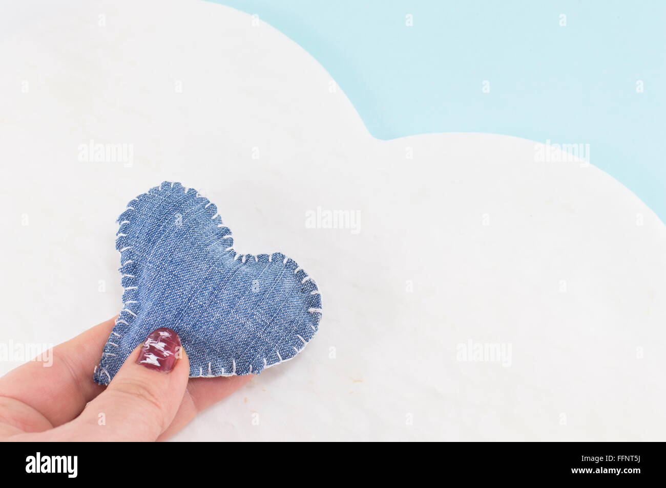 Denim-Herz in Frauenhand gegen ein Cloud-design Stockfoto