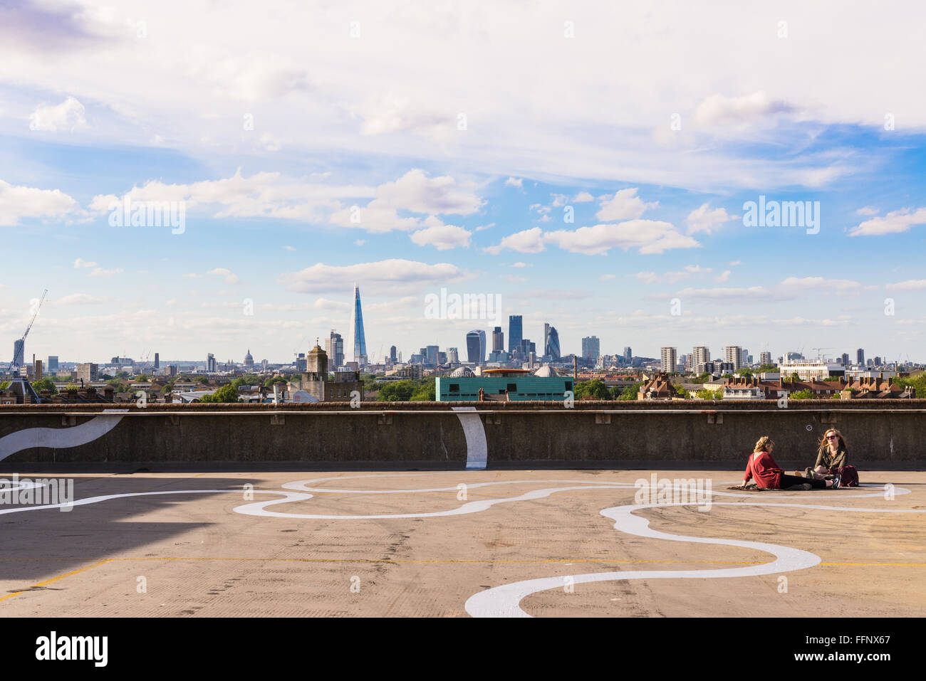 Zwei Mädchen trinken Bier, während sie sich auf dem Boden des Café Franks Cafe auf der Dachterrasse in Peckham, einem coolen Viertel im Südosten Londons, niederlassen. Stockfoto