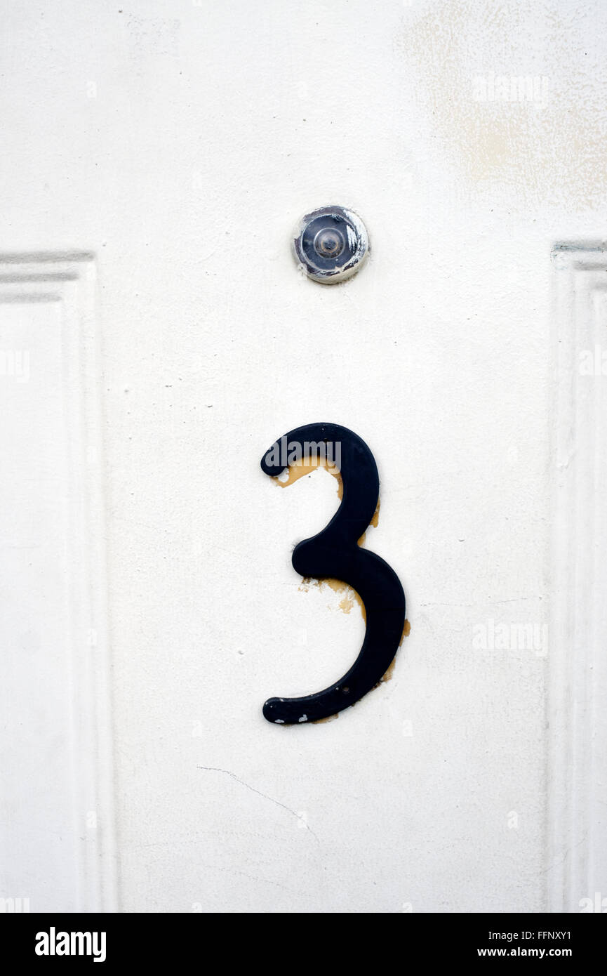 Hausnummer drei auf eine weiße Holztür mit Guckloch Stockfoto