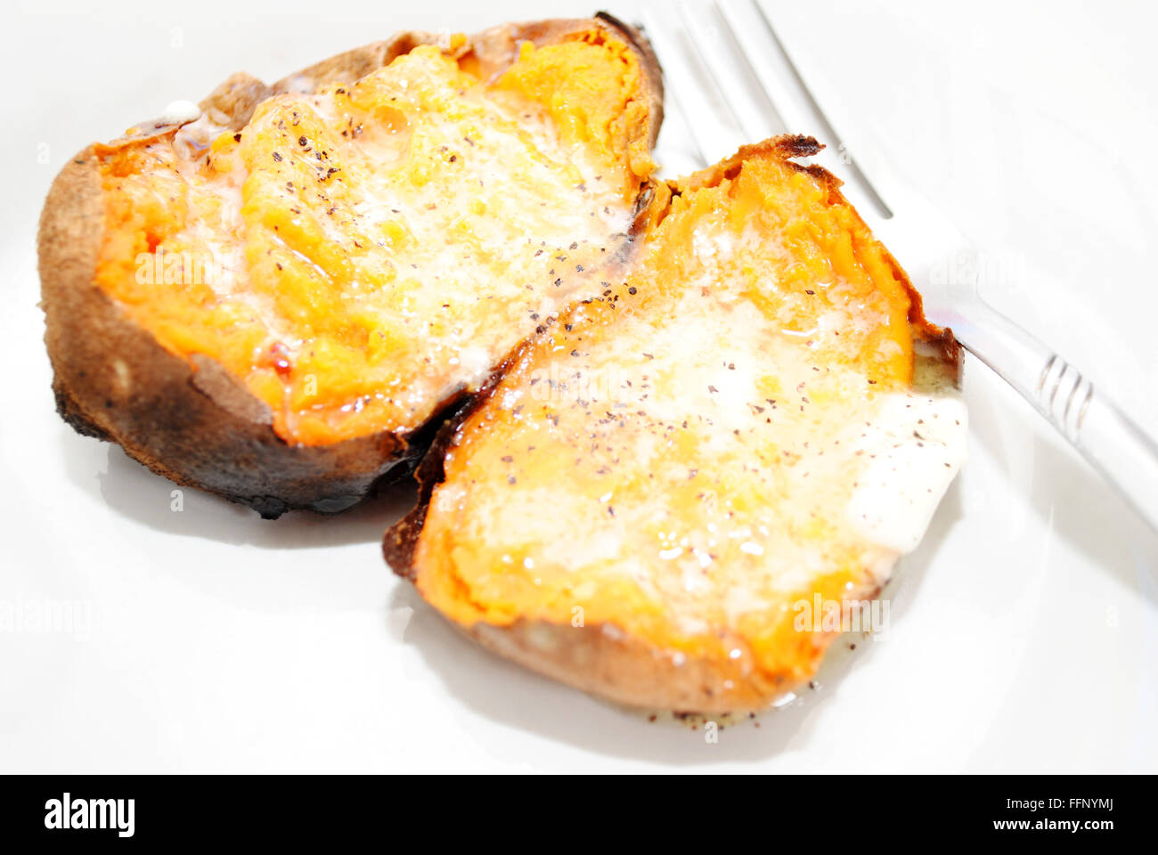 Leckere süße Kartoffeln mit zerlassener Butter und Pfeffer Stockfoto