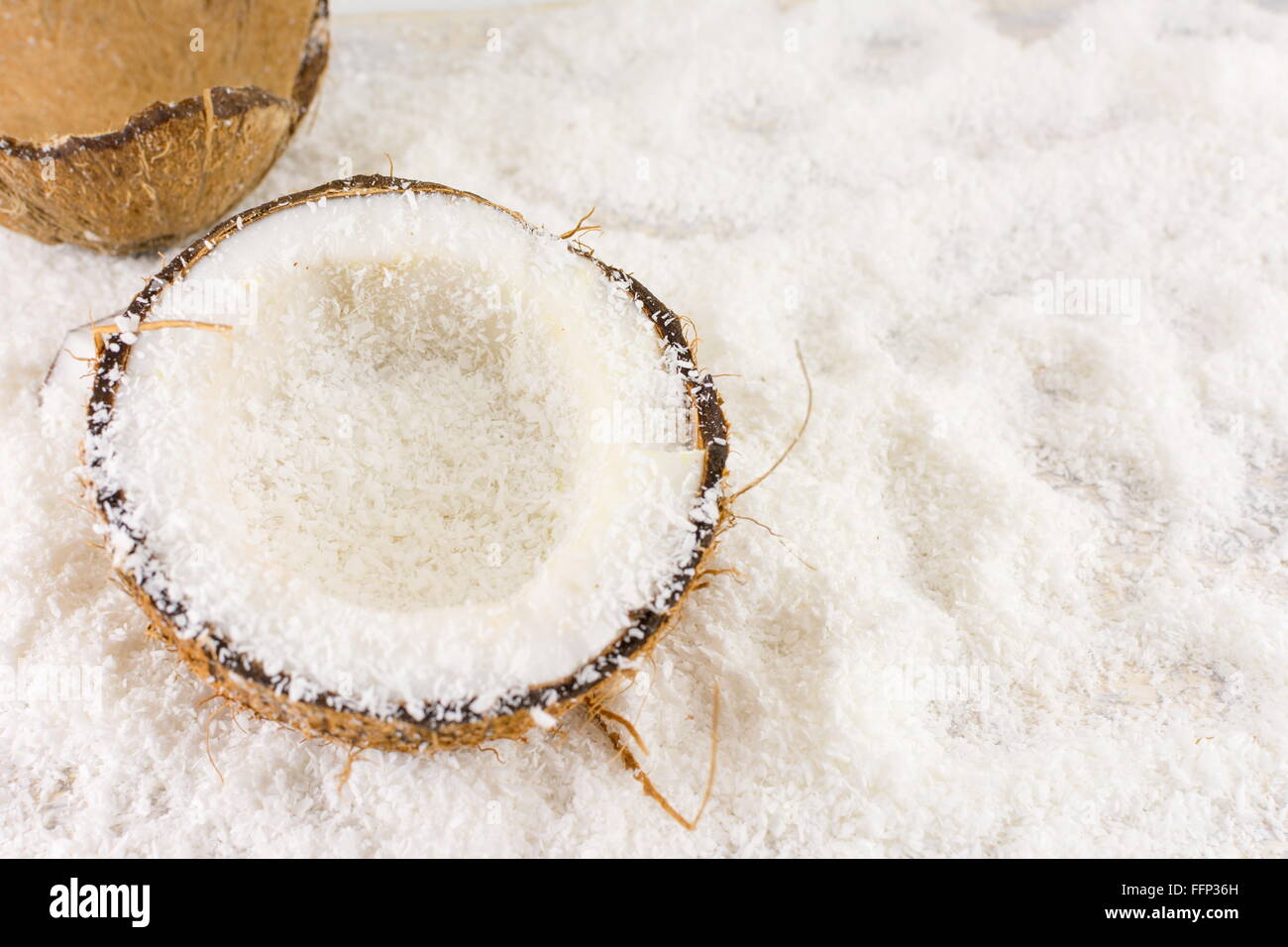 Halbierte frische Kokosnuss und Kokos Pulver auf dem Tisch Stockfoto