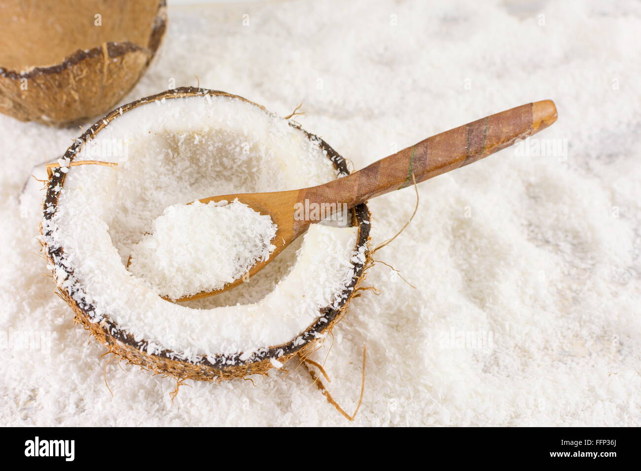 Halbierte frische Kokosnuss und Kokos Pulver auf dem Tisch Stockfoto