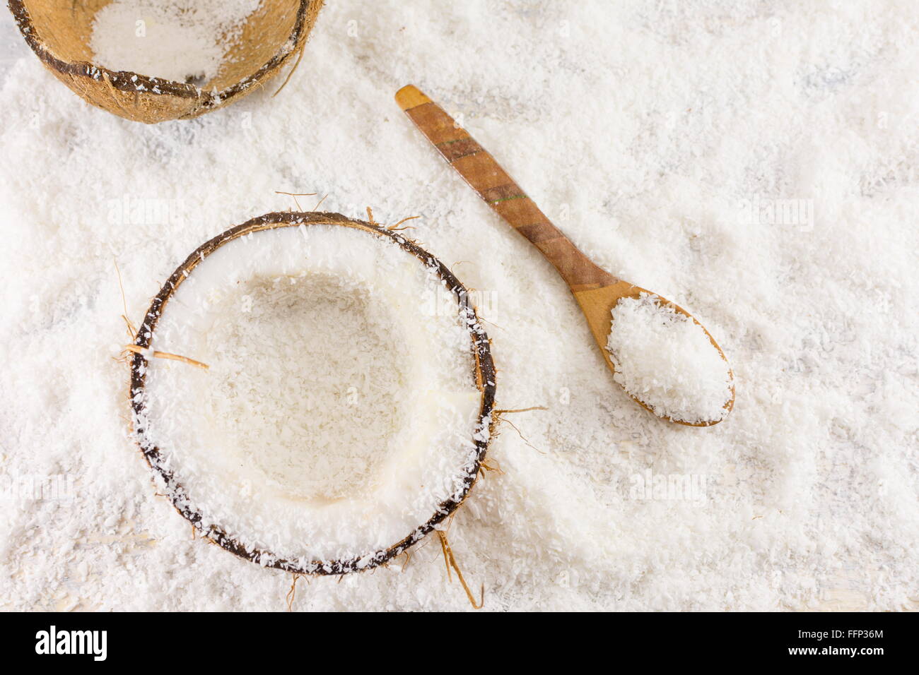 Halbierte frische Kokosnuss und Kokos Pulver auf dem Tisch Stockfoto