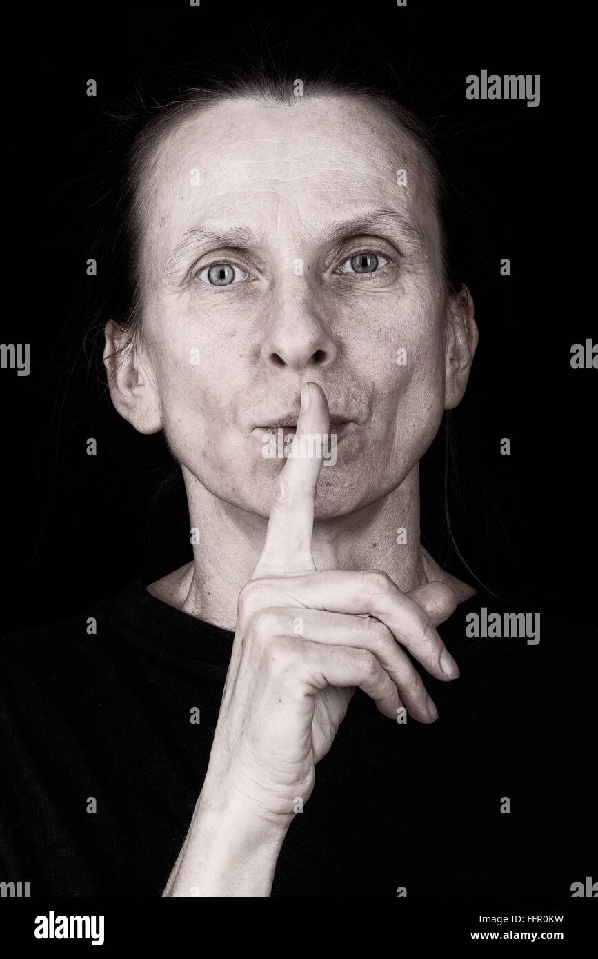 Porträt einer attraktive Erwachsene Frau setzen die Finger vor den Mund und sagen: "Sei still!" Stockfoto