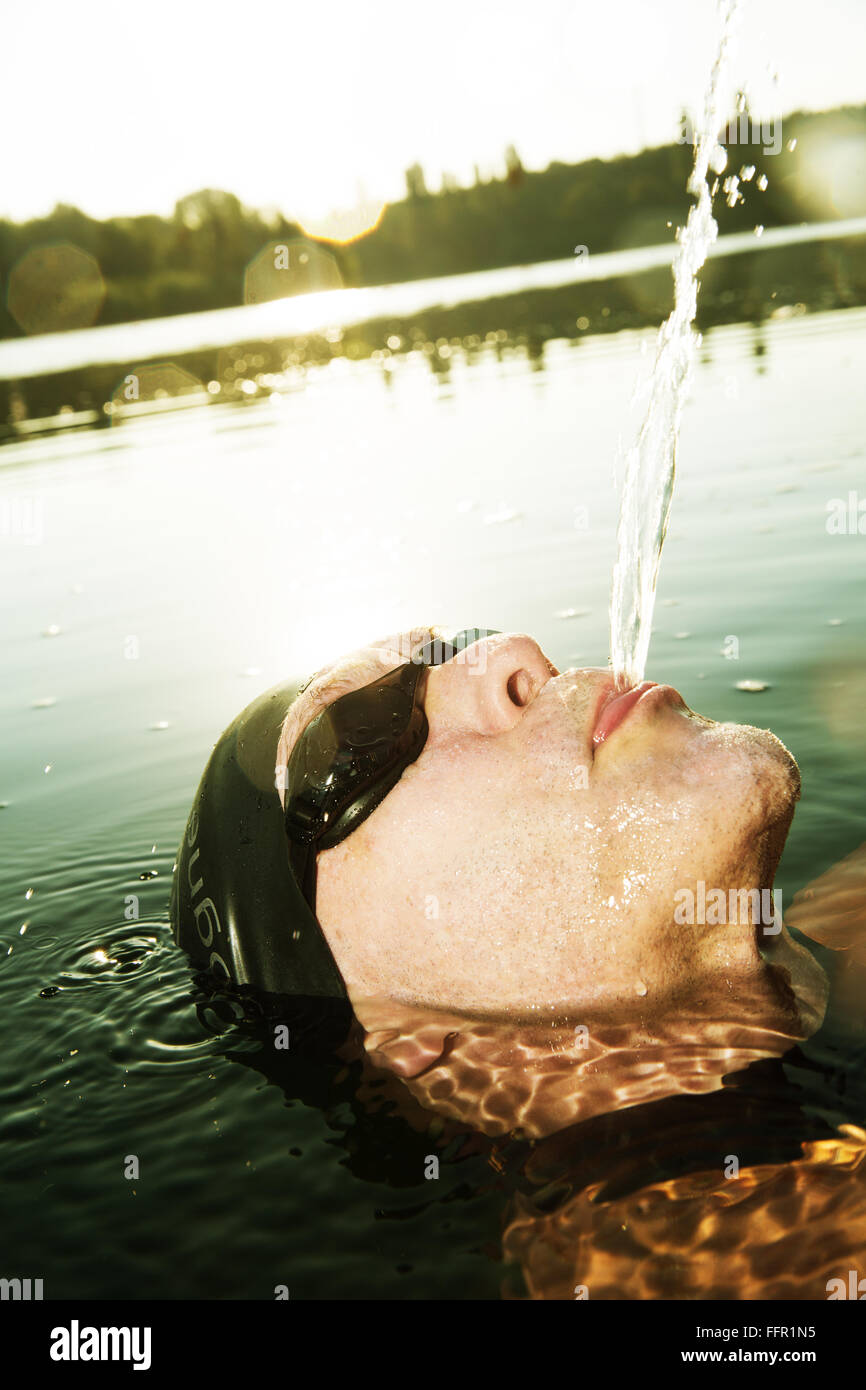 Mann mit Schwimmbrille spucken Wasser im See, Deutschland Stockfoto