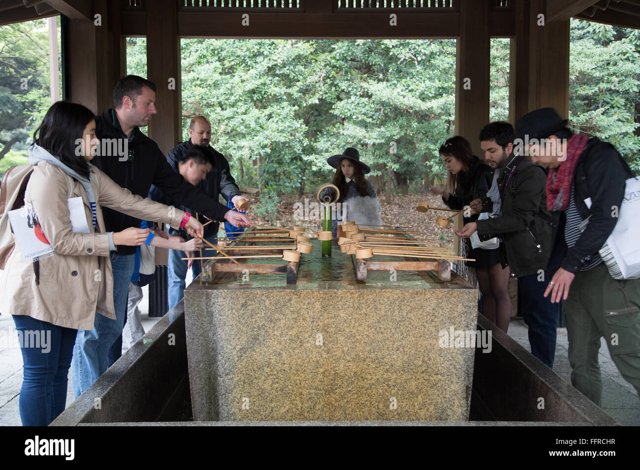 Besucher der Meiji-Schrein in Tokio, die sich durch Ausführen von Temizu auf eine Hand Waschbecken vor dem Betreten reinigen. Stockfoto