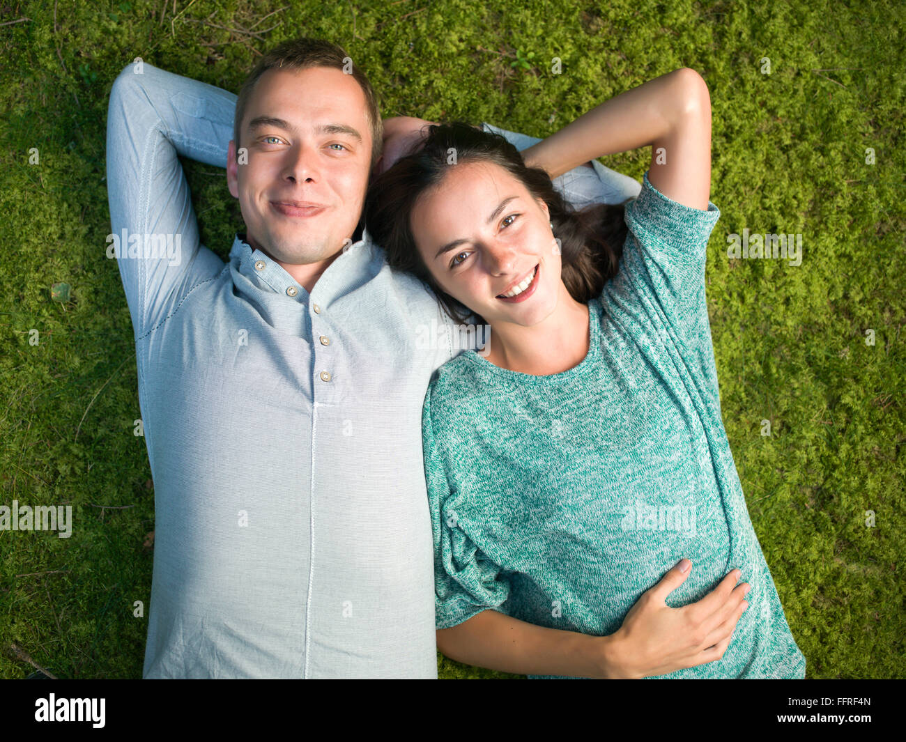 junges Paar auf grünem Moos liegend entspannen genießen Natur lächelnd Stockfoto