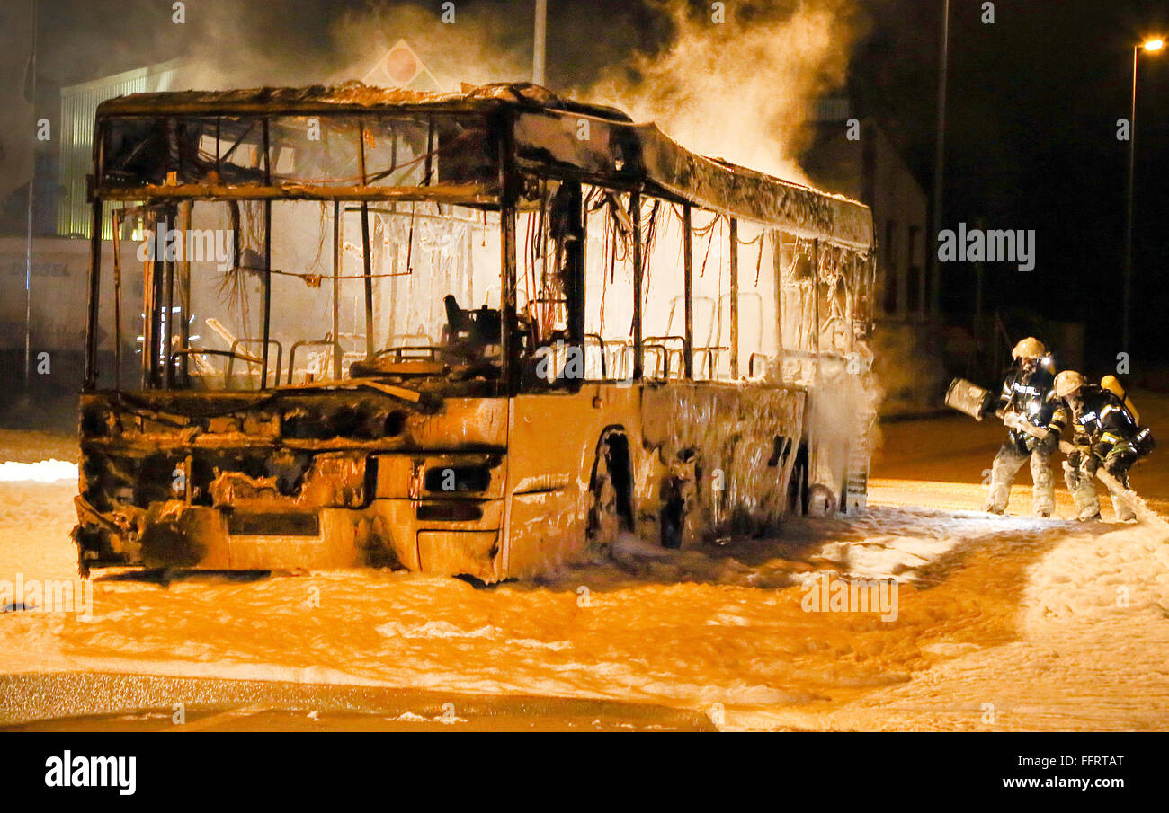 Niederkassel, Deutschland. 16. Februar 2016. Feuerwehrleute stehen neben einem ausgebrannten Bus in der Nähe von einem Gas statin in Niederkassel, Deutschland, 16. Februar 2016. Der 64 Jahre alte Busfahrer Dämpfe am Fahrzeug beim Pumpen Gas entdeckt. In wenigen Minuten der Bus komplett ausgebrannt. Die Flammen hinter einem geparkten Auto erreicht und verursacht Schäden an der Straße. Die Kosten der Schäden belaufen sich auf rund 100.000 Euro. Niemand wurde verletzt. Ursache des Feuers war zunächst unklar. Foto: JENS KLEINERT/Dpa/Alamy Live News Stockfoto