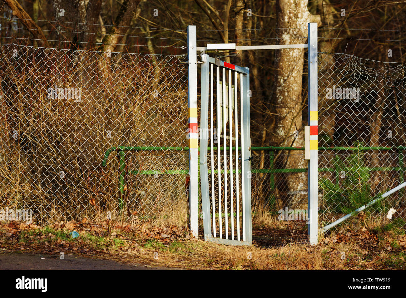 Eine offene Aluminium-Tor mit saldierten Zaun auf beiden Seiten. Tor ist etwas gebogen, was darauf gewaltsames Eindringen hindeutet. Zaun ist beschädigt. Stockfoto