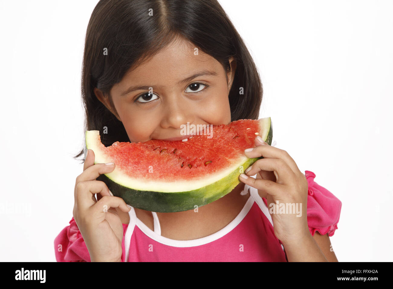 Acht Jahre altes Mädchen hält halb runde Scheibe Wassermelone und Essen es Herr #703U Stockfoto