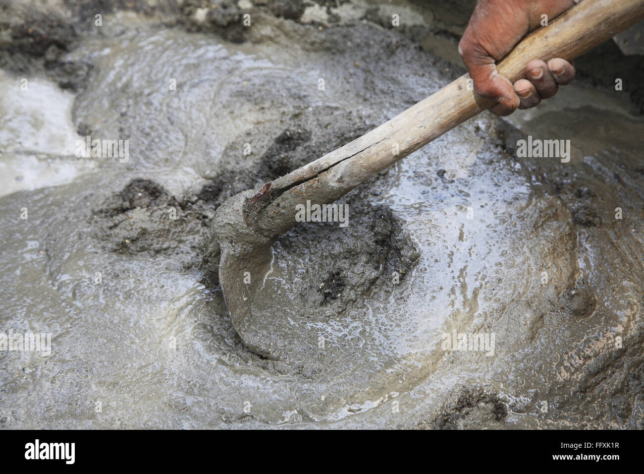 Manuell mischen von Zement, Sand und Wasser für Putz mit Hilfe von Spaten Hacke Stockfoto