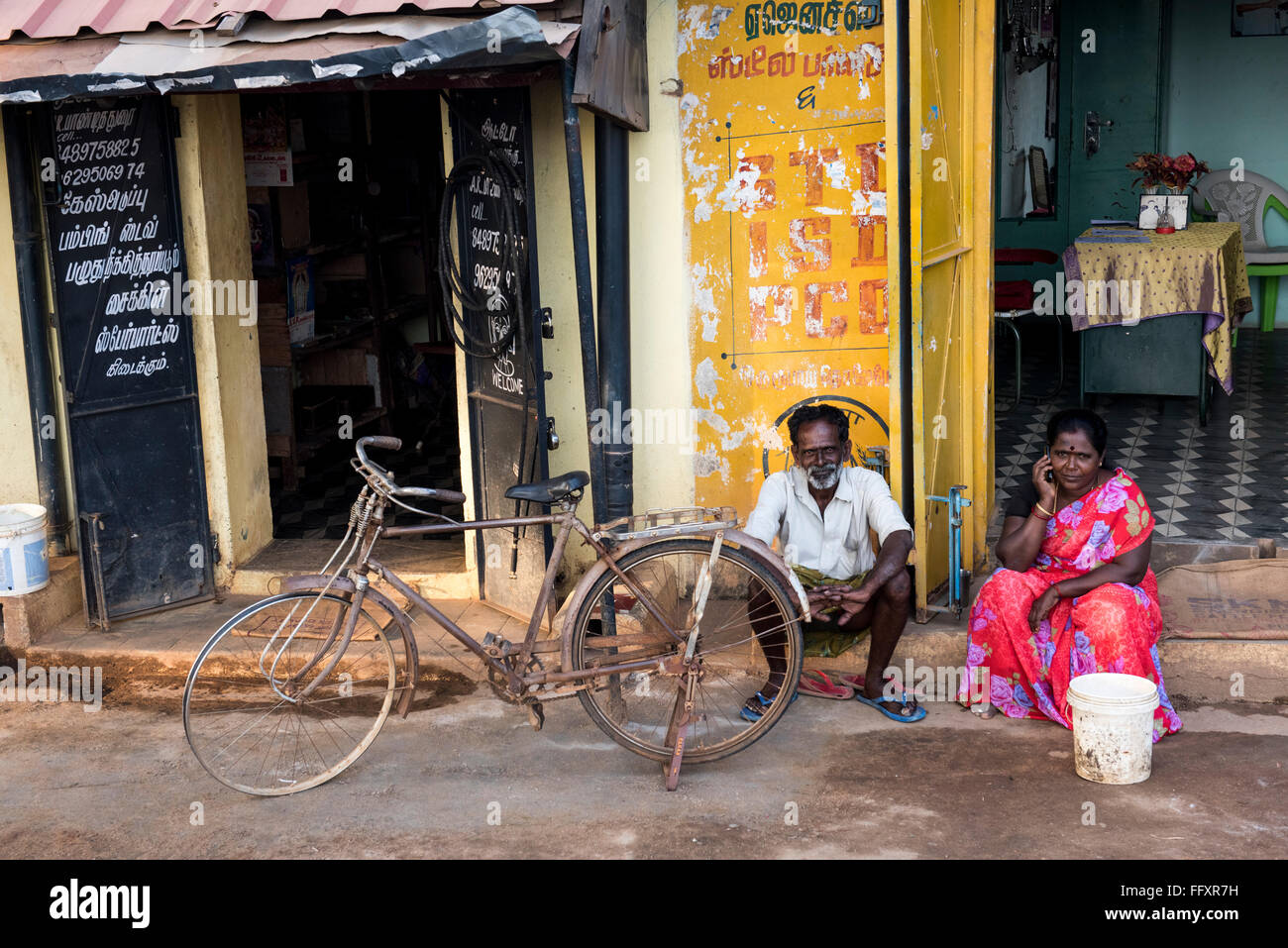 Ein indischer Mann und einer indischen Frau sitzen vor einem Geschäft im Dorf Kundrikudy in der Nähe von Chettinad, Tamil Nadu, Indien Asien Stockfoto