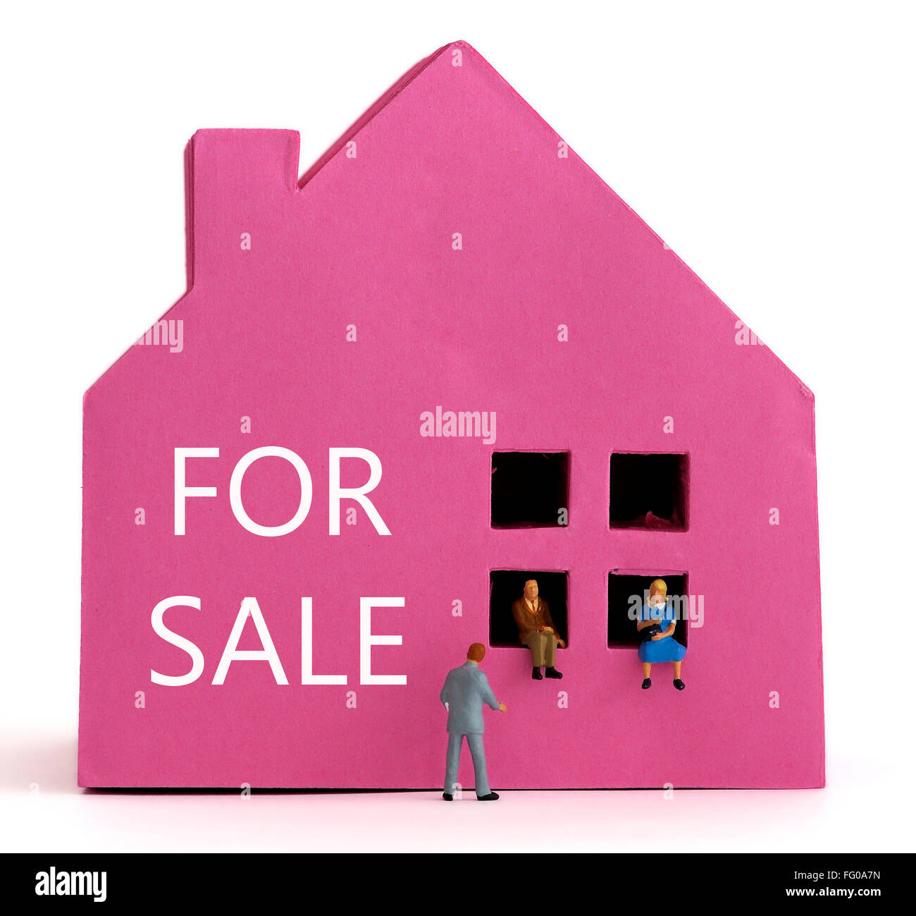Ein rosa Papier-Haus und ein paar sitzen in den Fenstern mit einem Immobilienmakler in einem Anzug. Haus Kauf Verkauf-Konzept. Stockfoto