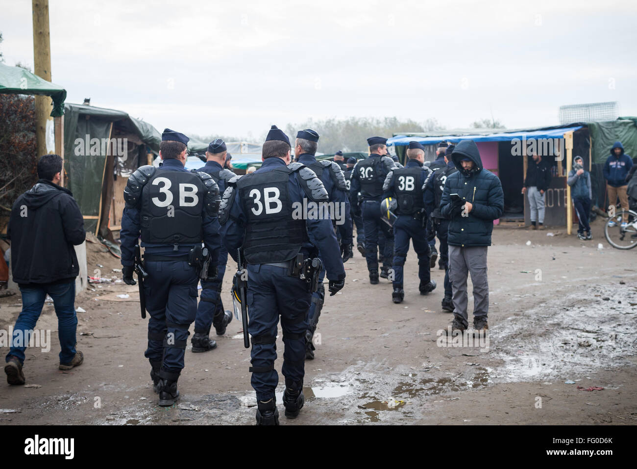 Bewaffnete französische Polizei geht durch das Dschungel-Flüchtlingslager, Calais, Frankreich. Stockfoto