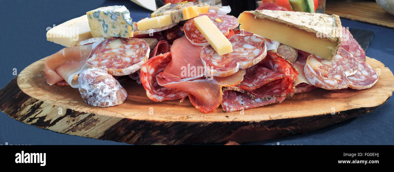 Stücke von Gourmet-Kuh- und Ziegenmilch Käse, Leber Pastete, Wurstwaren, Fette Wurst und Salami geschnitten serviert auf einem Stück Holz Stockfoto