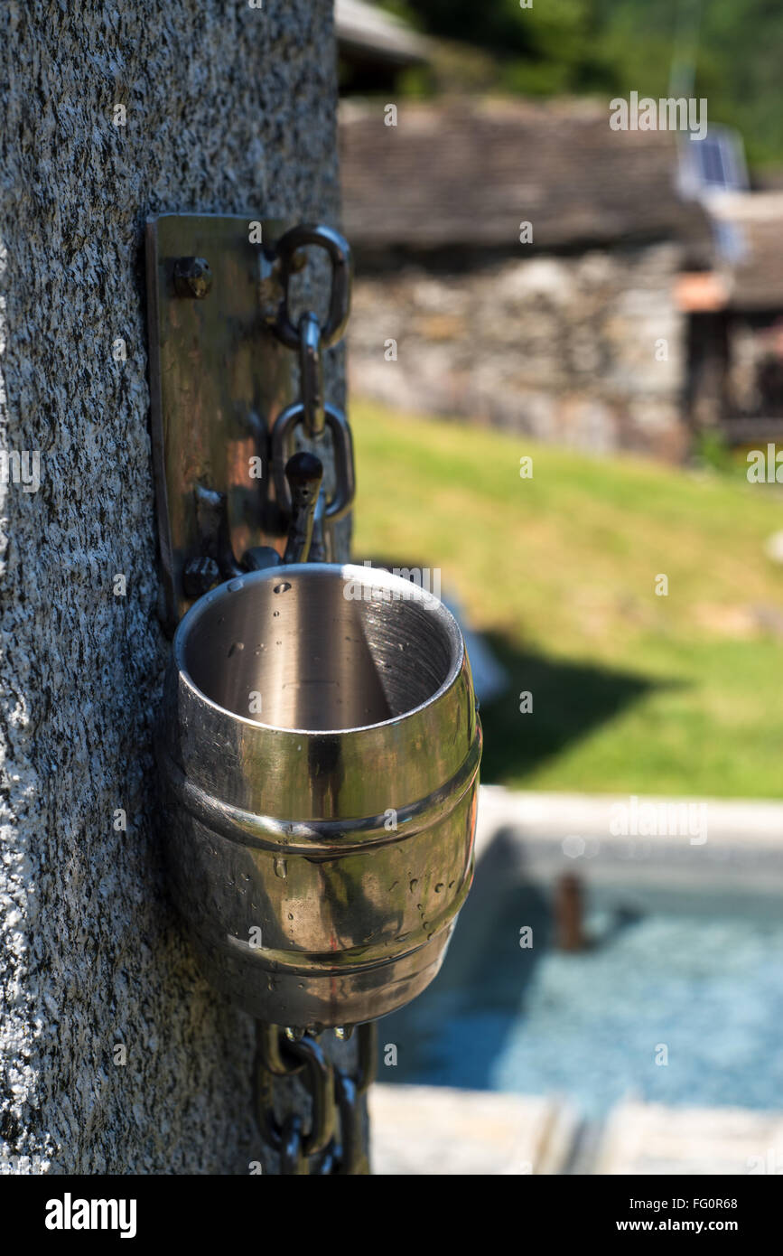 Stahl Becher bereit, von jedem Durst an einem Brunnen in Val Grande National Wilderness Area, italienischen Alpen genutzt werden Stockfoto