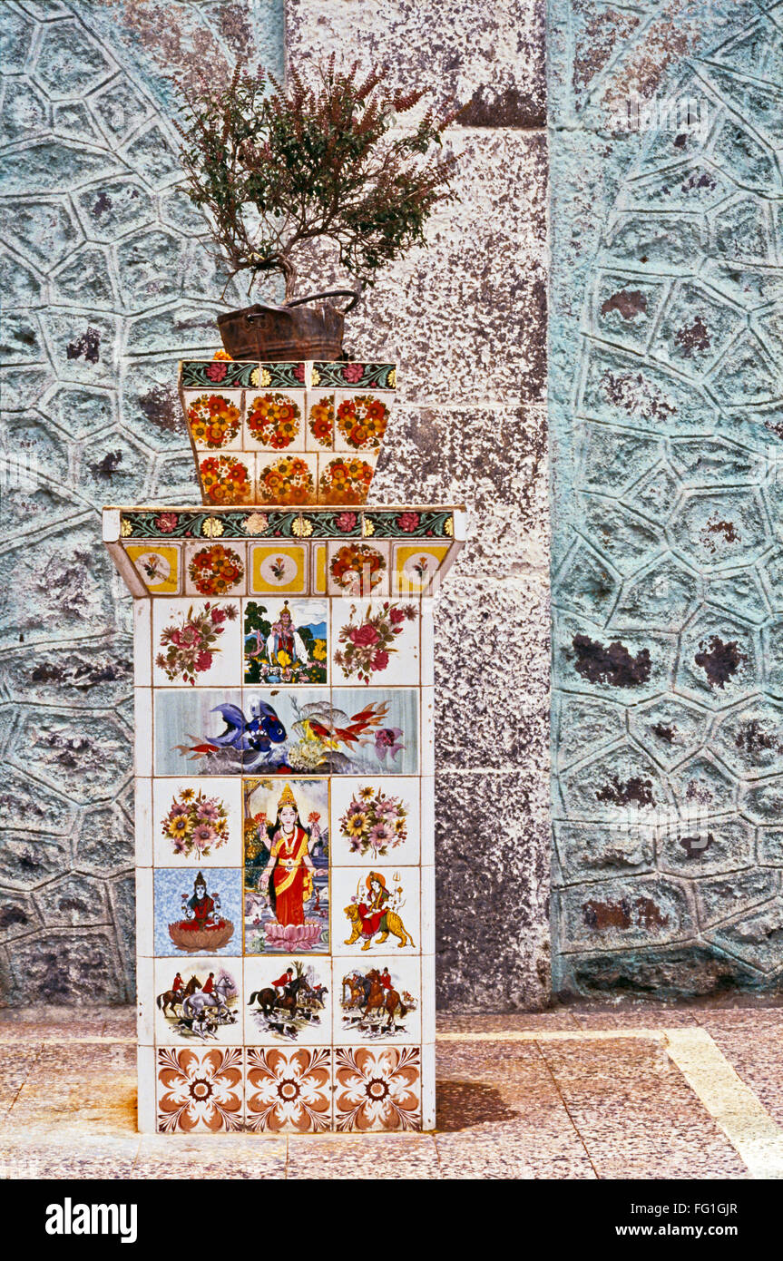 Tulsi-Pflanze auf Sockel, verziert mit keramischen Fliesen bedruckt mit Bildern der indischen Götter und Göttinnen Stockfoto